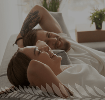 Couple Smiling while Laying on Couch Together