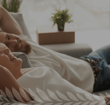 Couple Smiling while Laying on Couch Together
