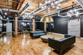 A room with a black couch and a wooden floor. at Montgomery Mill Apartments in Windsor Locks, CT