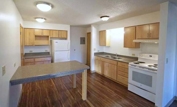an empty kitchen with wood flooring and white appliances