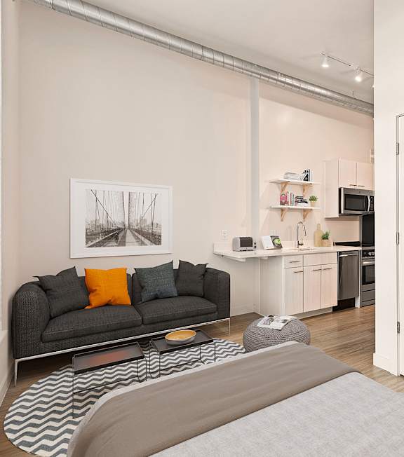 A living room with a grey couch and a grey rug. at RiDE at RiNo Apartments, Colorado