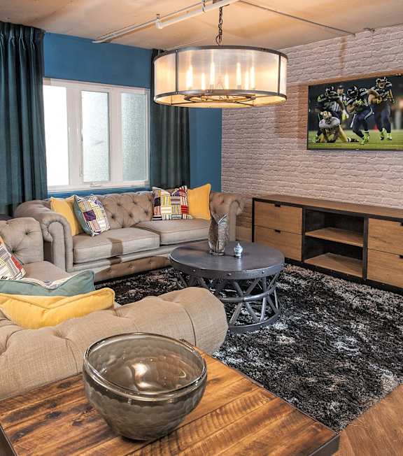 A grey bowl is on a wooden table in a room with a grey sofa and a black rug.