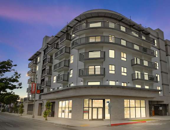 a large grey building with many windows and balconies at The Fairfax Flats Apartments, Los Angeles, CA, 90019