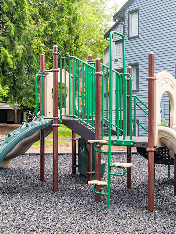 A playground with a green slide and a brown slide.