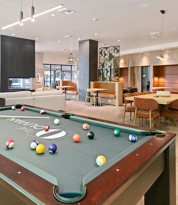 A pool table is in the middle of a room with a dining table and chairs.