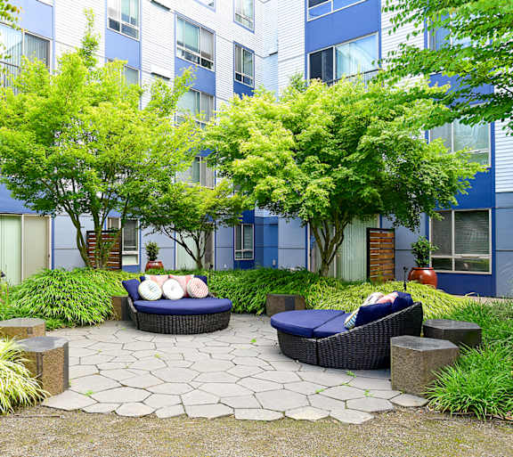 a courtyard with couches and trees in front of an apartment building