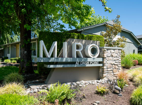 a sign in front of a house with a lawn and trees