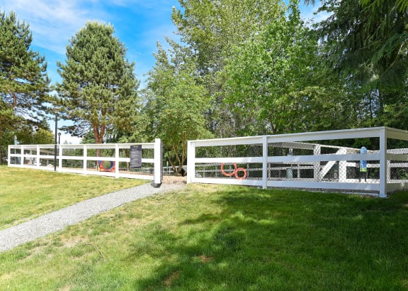 a white fence in a grassy area with trees in the background