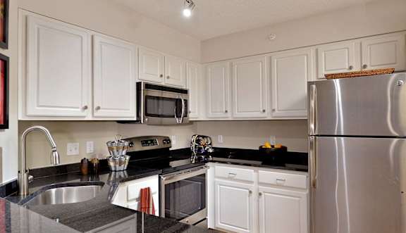 A kitchen with white cabinets and a stainless steel refrigerator.