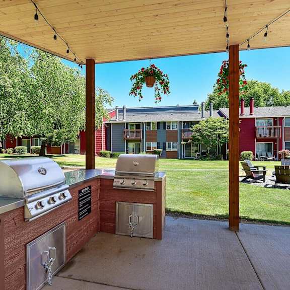 A barbecue grill is set up under a wooden canopy.