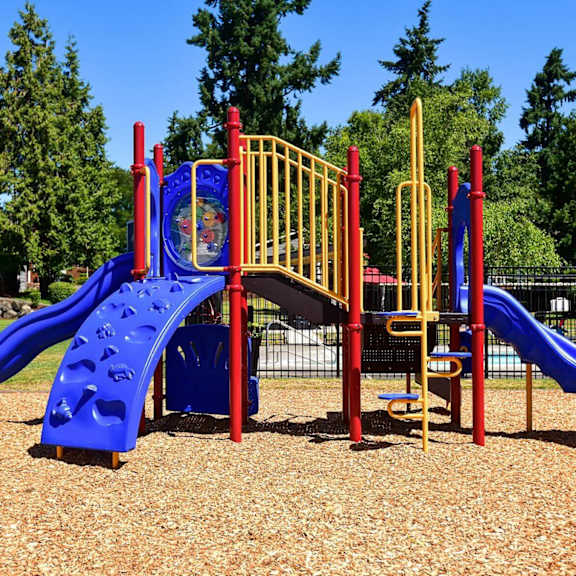 A playground with a blue slide and a yellow and red structure.