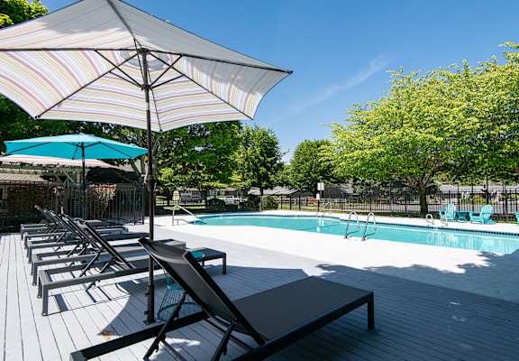 a swimming pool with chairs and an umbrella next to it