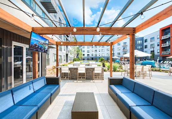 A wooden pergola with a screen and blue couches.