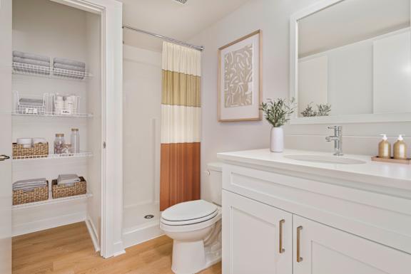A bathroom with a white toilet, sink, and cabinets.