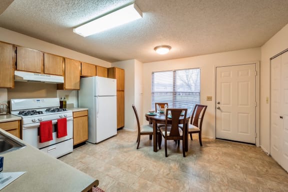 a kitchen with a dining table and a white stove and refrigerator at MeadowView Townhomes, Goshen, Ohio