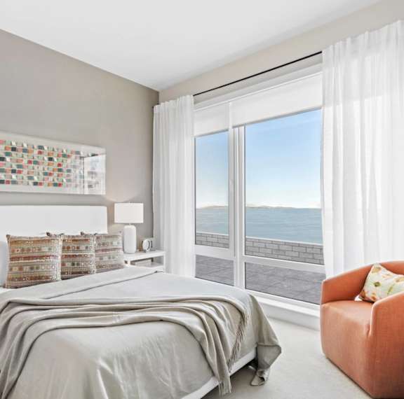 A bedroom with a large bed and a chair.