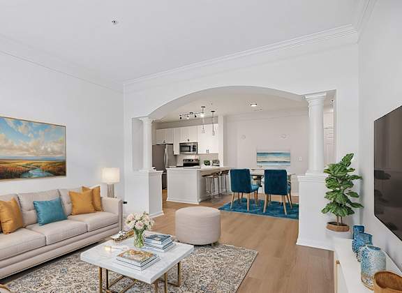 A living room with a beige couch, a coffee table, and a painting on the wall.