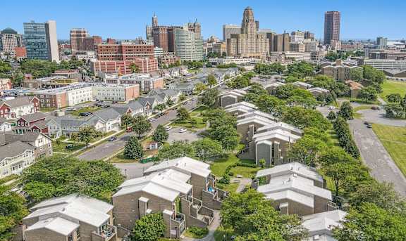 an aerial view of a cluster of houses with trees and a city skyline in the background at Shoreline Apartments, Buffalo, New York