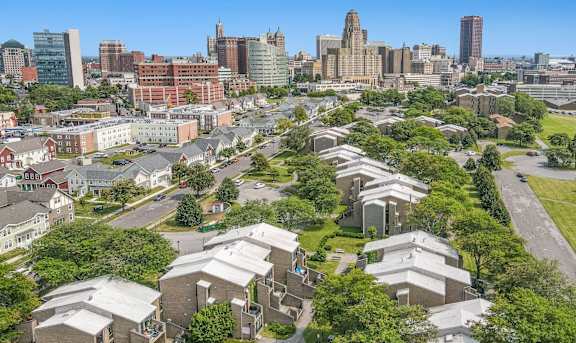 an aerial view of a cluster of houses with trees and a city skyline in the background at Shoreline Apartments, Buffalo, New York