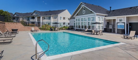 A swimming pool in a residential area with houses in the background. at The Village at Westmeadow, Colorado, 80906