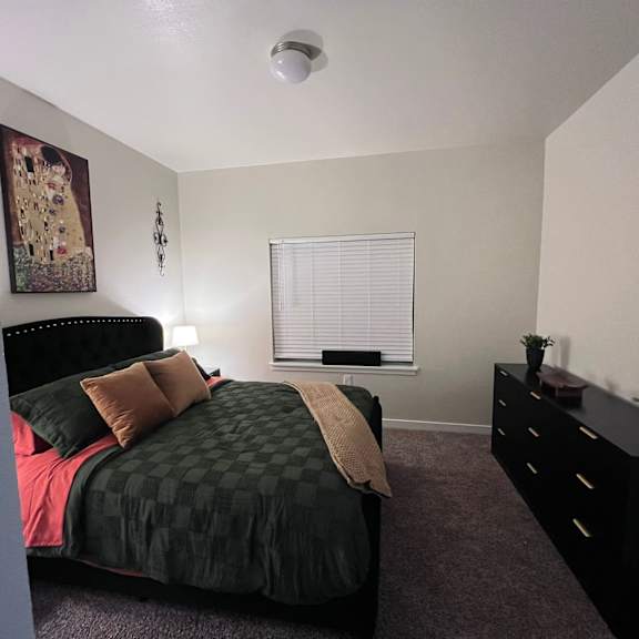 A bedroom with a bed, dresser, and window.