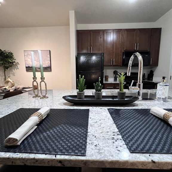 A kitchen with a black refrigerator and brown cabinets.