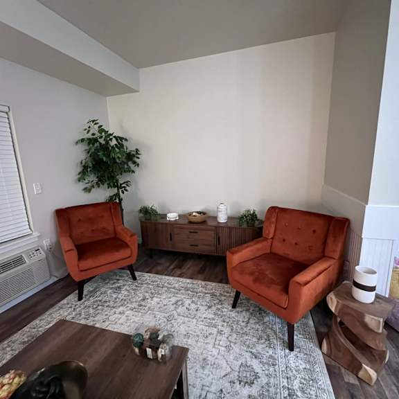A living room with two red chairs and a wooden coffee table.