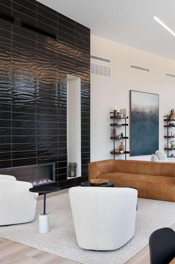 A modern living room with a fireplace and a brown couch.
