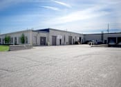 Thumbnail 2 of 4 - A large industrial building with a parking lot in front.