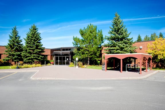 A parking lot with a building and trees in the background.
