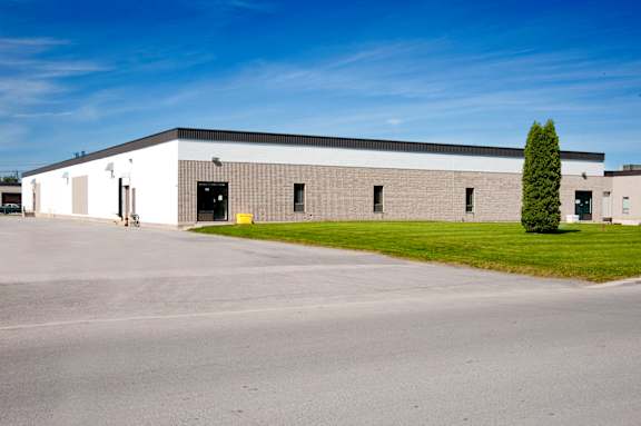 A large industrial building with a parking lot in front.