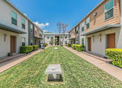 Thumbnail 13 of 30 - Courtyard with manicured lawns and shade trees between apartment buildings