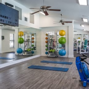 a spacious fitness center with yoga equipment and a flat screen tv