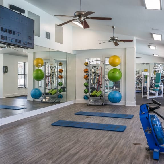 a spacious fitness center with yoga equipment and a flat screen tv at The Monroe Apartment Homes, Florida, 32303