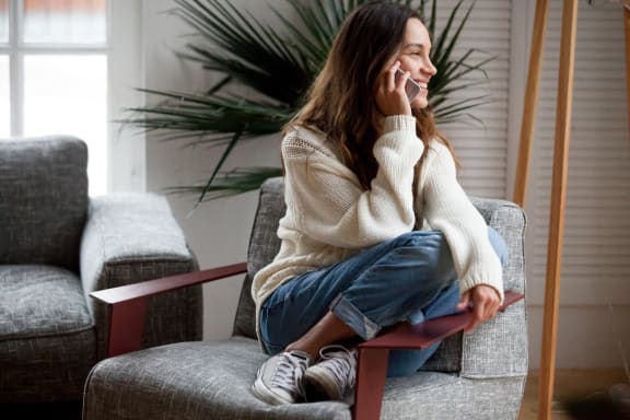a woman sitting on a chair talking on her cell phone