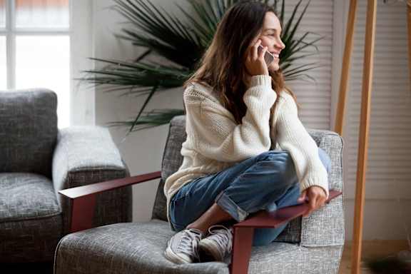 a woman sitting on a chair talking on her cell phone