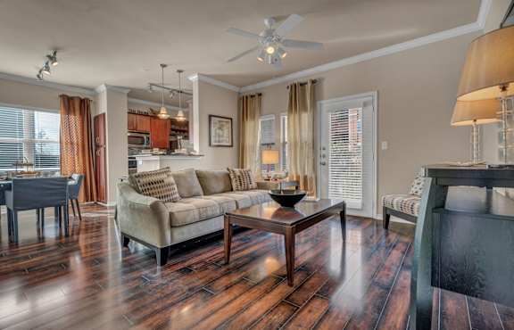 A living room with a grey couch, a coffee table, and a brick wall.