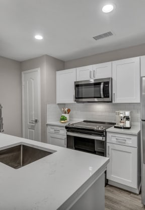 a white kitchen with stainless steel appliances and a sink at River Stone Ranch, Austin, TX, 78749