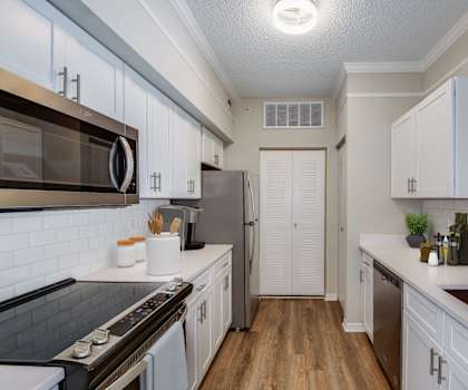 a kitchen with white cabinets and stainless steel appliances at The Ashlar, Fort Myers, FL, 33907