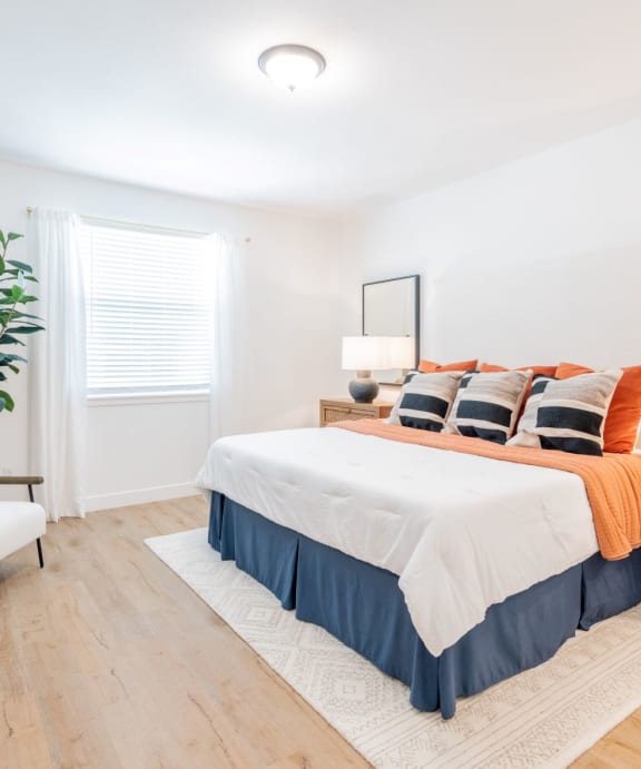 A bedroom with a bed, nightstand, and chair.at Crocker Village – Single Family Homes, Sacramento California