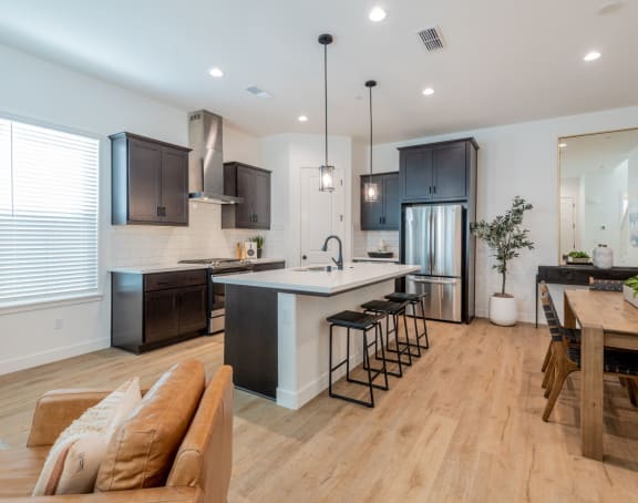 A modern kitchen with dark brown cabinets and a wooden floor.at Crocker Village – Single Family Homes, Sacramento