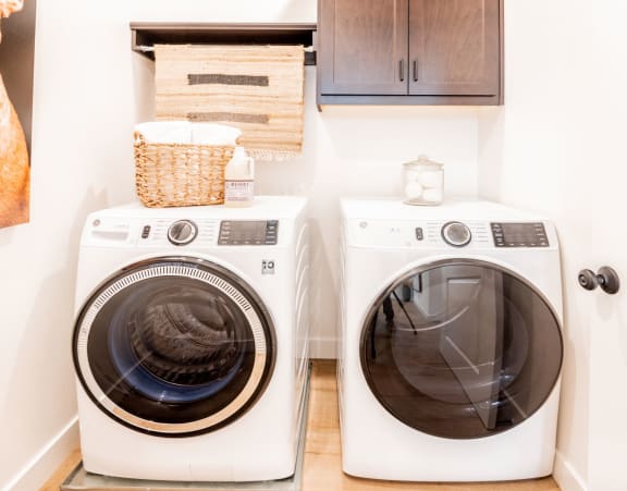 Two white front loading washing machines in a laundry room.at Crocker Village – Single Family Homes, California