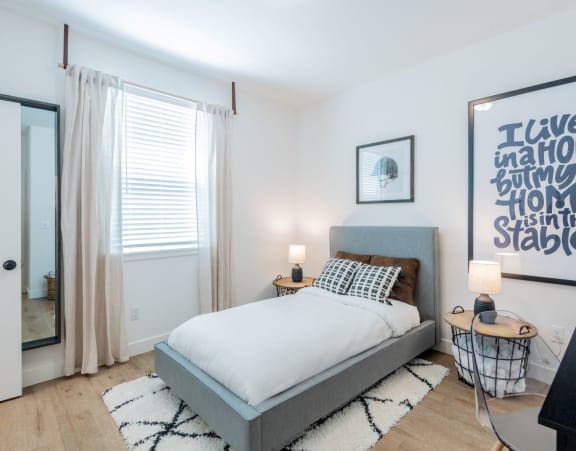 A bedroom with a bed, a desk, and a framed quote on the wall.at Crocker Village – Single Family Homes, Sacramento
