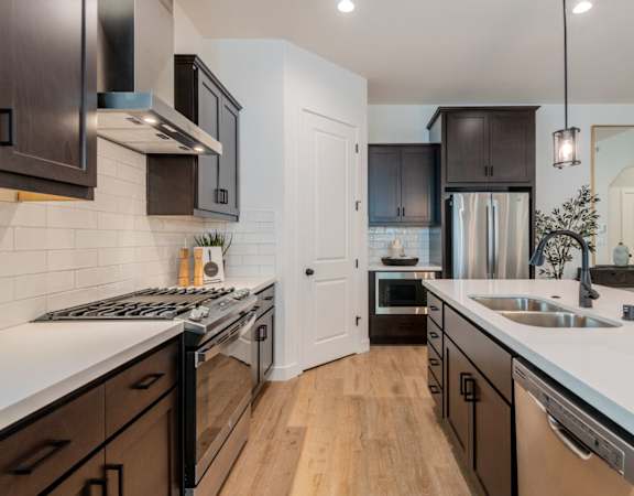 A modern kitchen with dark brown cabinets and white countertops.at Crocker Village – Single Family Homes, Sacramento California