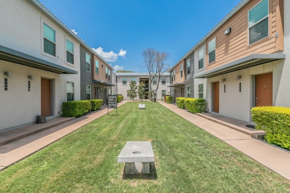 Courtyard with manicured lawns and shade trees between apartment buildings