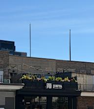 A building with a sign that reads "JINYA" and a balcony with plants.