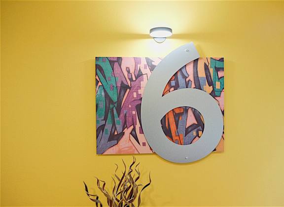 a large metal number six hanging on a yellow wall