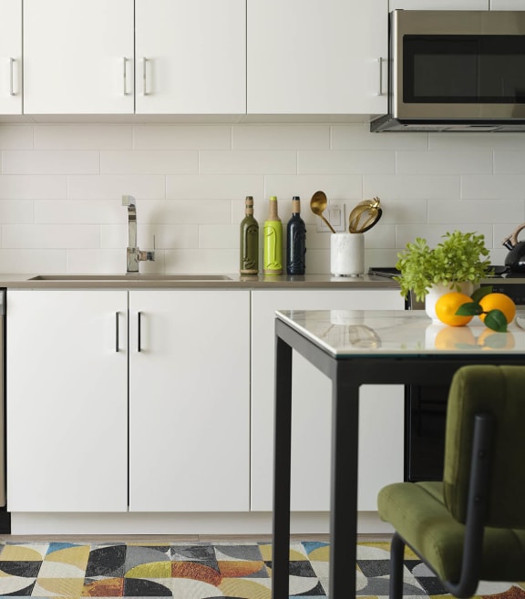 a small kitchen with white cabinets and a table