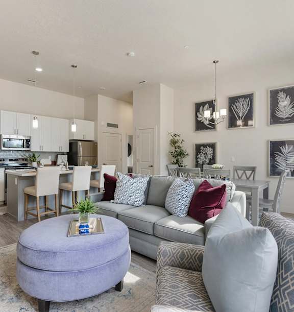 A modern living room with a grey couch and a round ottoman.