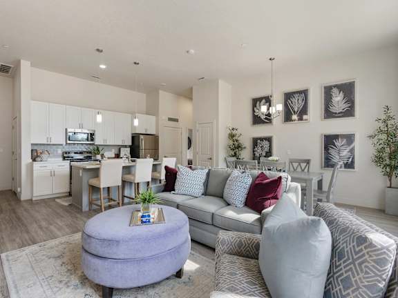 A modern living room with a grey couch and a round ottoman.